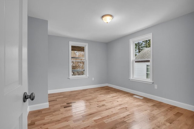 empty room featuring a healthy amount of sunlight and light hardwood / wood-style floors