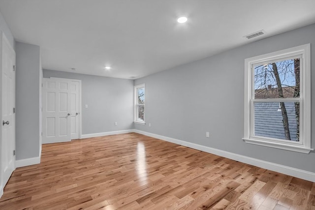 unfurnished room with a healthy amount of sunlight and light hardwood / wood-style floors