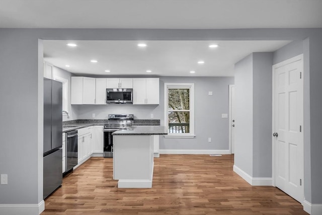 kitchen with a center island, white cabinets, light hardwood / wood-style flooring, and appliances with stainless steel finishes