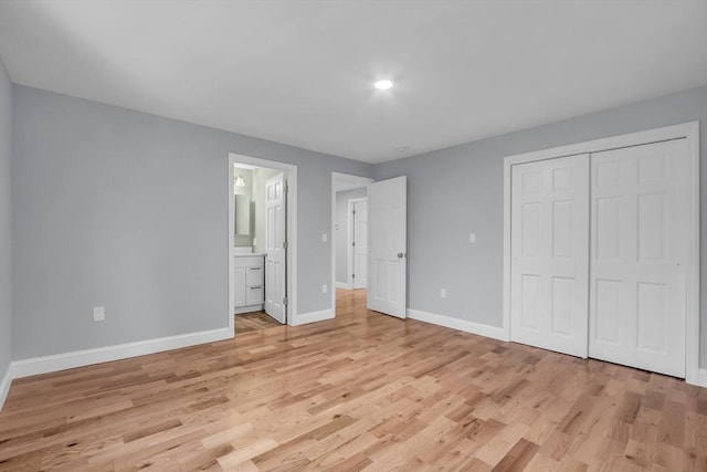 unfurnished bedroom with ensuite bath, a closet, and light hardwood / wood-style floors