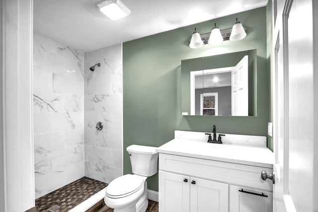 bathroom featuring tiled shower, vanity, hardwood / wood-style flooring, and toilet