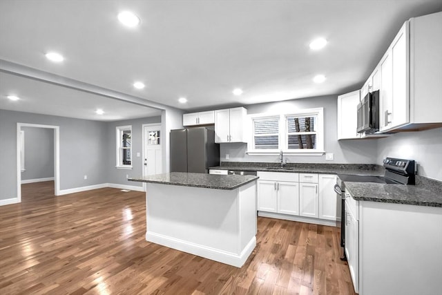 kitchen featuring wood-type flooring, stainless steel appliances, a kitchen island, and white cabinetry