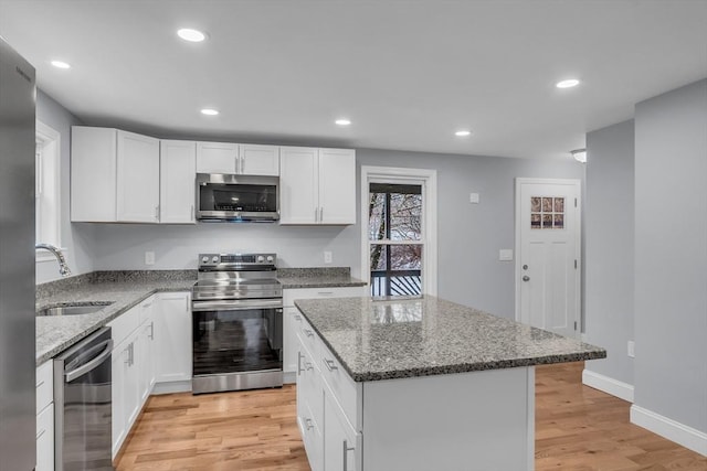 kitchen with a center island, stainless steel appliances, white cabinetry, and sink