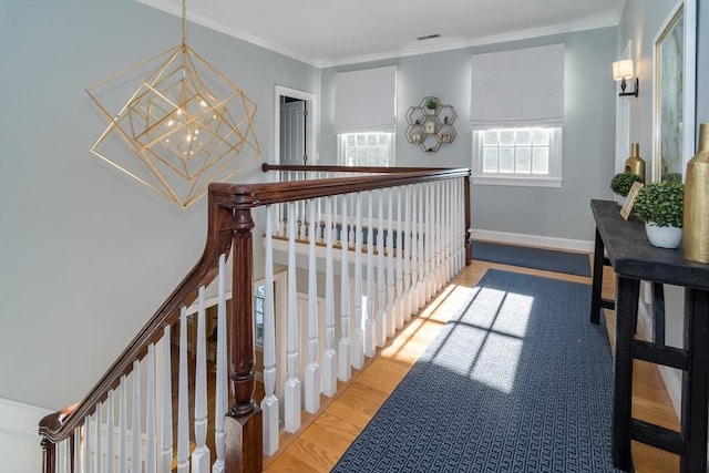 hallway featuring hardwood / wood-style flooring, crown molding, and a notable chandelier