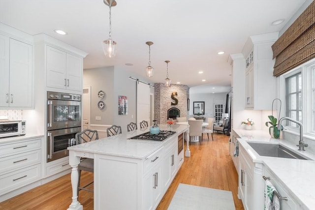 kitchen with sink, a breakfast bar area, white cabinets, hanging light fixtures, and stainless steel appliances