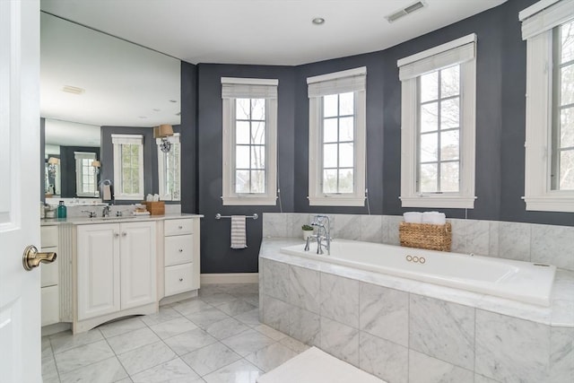 bathroom featuring vanity and tiled tub