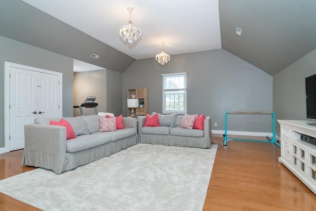 living room with an inviting chandelier, vaulted ceiling, and light wood-type flooring