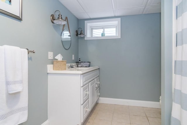 bathroom with a paneled ceiling, vanity, and tile patterned flooring