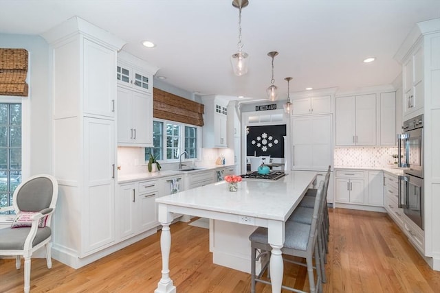 kitchen featuring pendant lighting, sink, a center island, and white cabinets