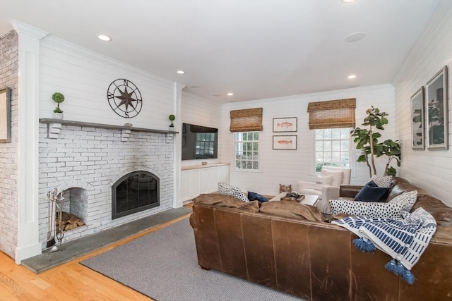 living room with hardwood / wood-style flooring, ornamental molding, and a brick fireplace