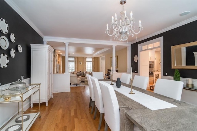 dining area with ornamental molding, light hardwood / wood-style floors, decorative columns, and a notable chandelier