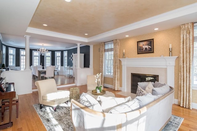 living room featuring ornate columns, a raised ceiling, a high end fireplace, and light hardwood / wood-style floors