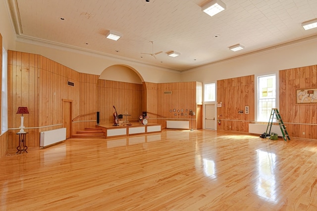 interior space featuring radiator heating unit, light hardwood / wood-style flooring, wooden walls, and ornamental molding