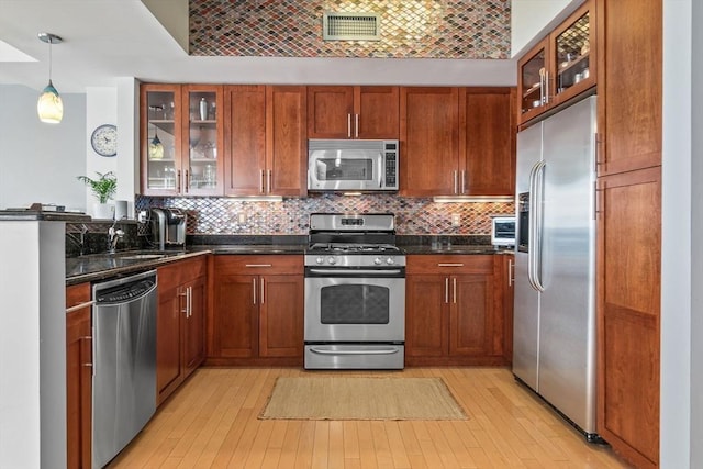 kitchen with light wood-type flooring, appliances with stainless steel finishes, brick ceiling, and decorative light fixtures