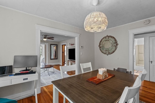 dining room featuring wood finished floors, ornamental molding, a chandelier, and a ceiling fan