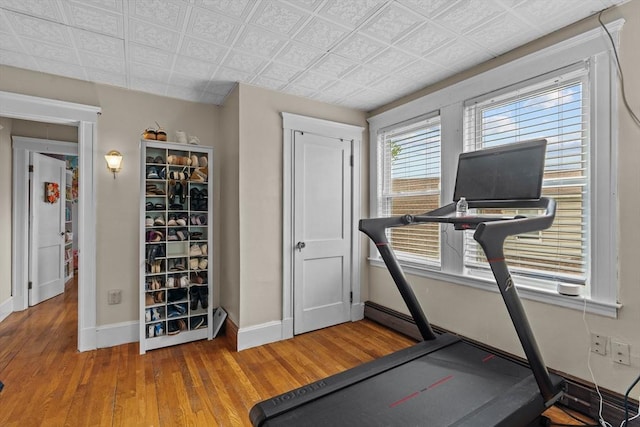 workout room with baseboards, wood finished floors, and an ornate ceiling