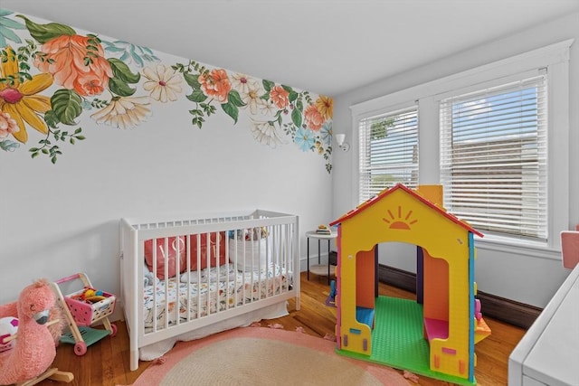 bedroom featuring wood finished floors and a nursery area