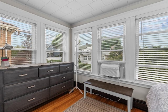 sitting room with wood finished floors, plenty of natural light, cooling unit, and crown molding