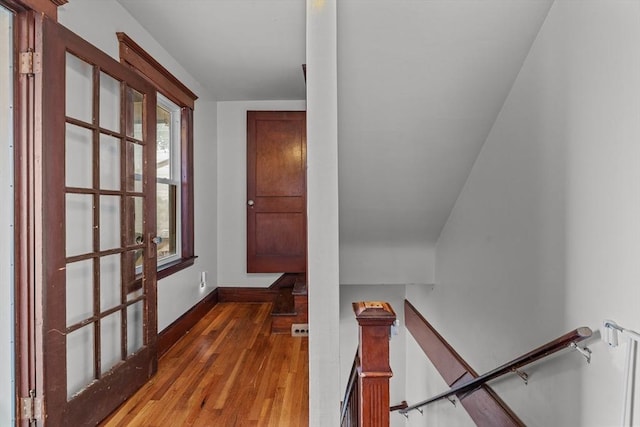 hallway featuring an upstairs landing, hardwood / wood-style floors, and baseboards