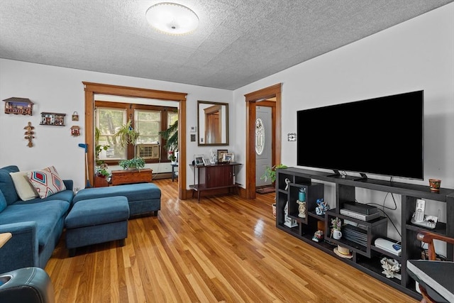 living area featuring light wood finished floors, a textured ceiling, and cooling unit