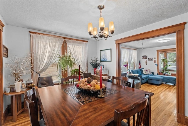 dining room featuring a chandelier, light wood finished floors, and a textured ceiling
