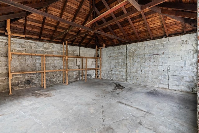 miscellaneous room with lofted ceiling, concrete flooring, and concrete block wall
