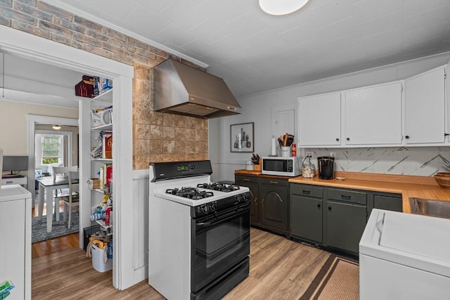 kitchen with wall chimney range hood, range with gas cooktop, light wood-style floors, and white cabinetry
