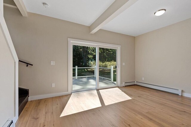 spare room with baseboard heating, beamed ceiling, and light wood-type flooring