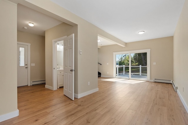 empty room featuring baseboard heating and light hardwood / wood-style floors