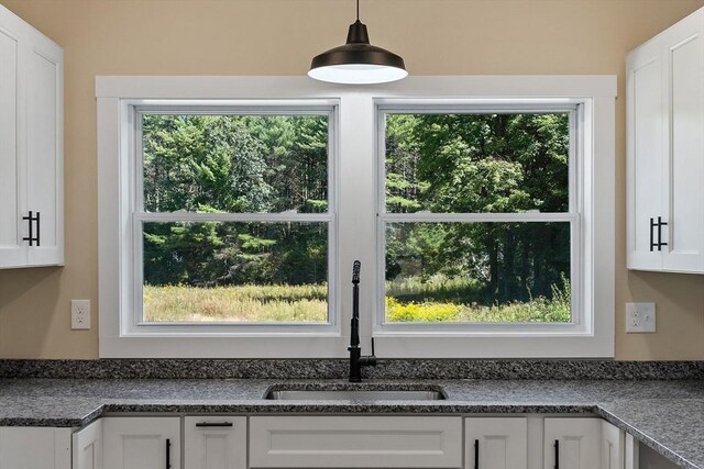 details with decorative light fixtures, white cabinets, and sink