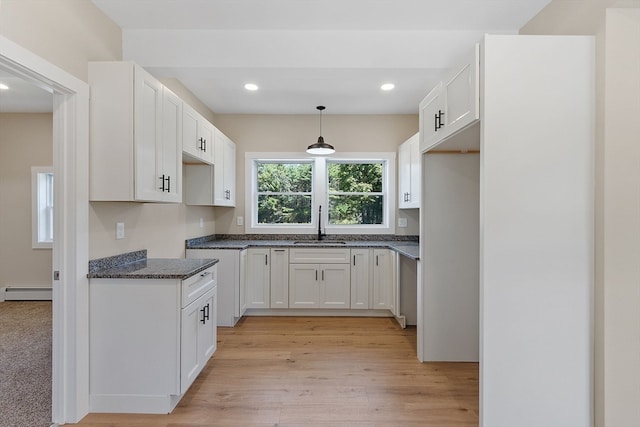 kitchen with light hardwood / wood-style flooring, baseboard heating, sink, hanging light fixtures, and white cabinets