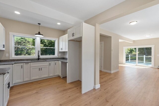 kitchen with white cabinets, hanging light fixtures, light hardwood / wood-style floors, and sink