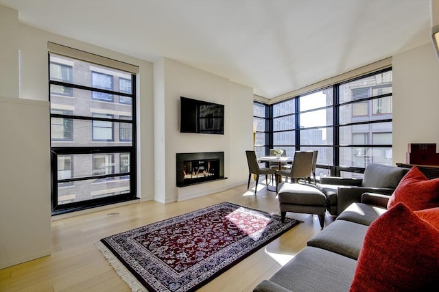 living room with a wealth of natural light, light hardwood / wood-style floors, and a wall of windows