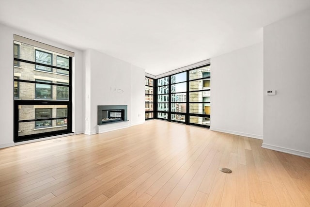 unfurnished living room featuring floor to ceiling windows, light wood-type flooring, and a wealth of natural light