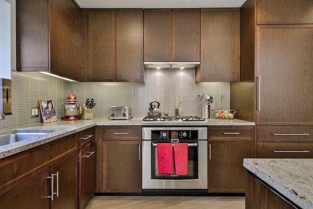 kitchen featuring light stone counters, backsplash, stainless steel appliances, and light hardwood / wood-style floors