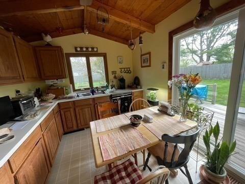 109 Wilder St, Swansea, MA 02777 - kitchen with dishwasher, wood ceiling, light countertops, brown cabinetry, and light tile patterned flooring