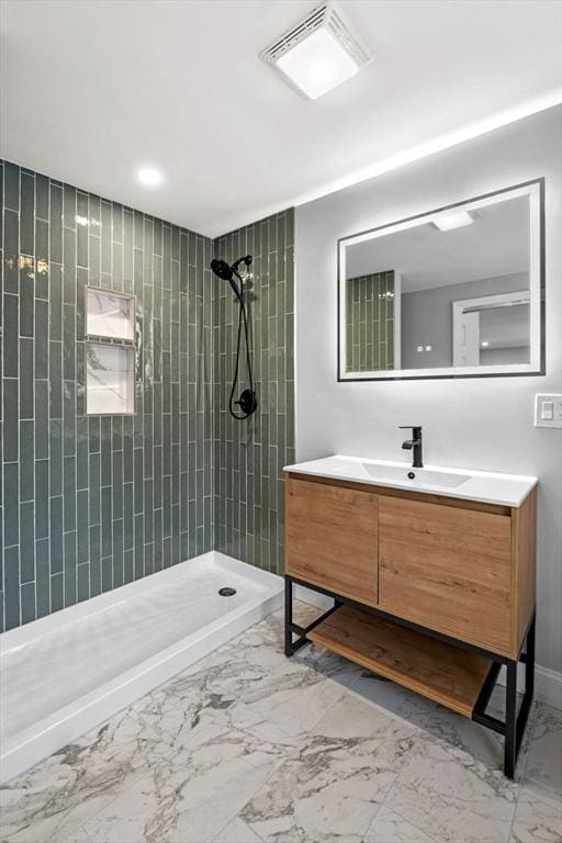 bathroom with a tile shower and vanity