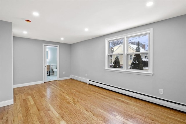 empty room with a baseboard heating unit and light hardwood / wood-style flooring