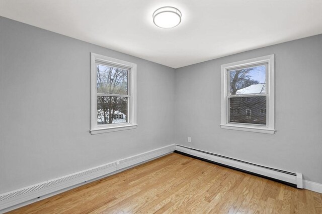 spare room featuring a baseboard heating unit and light hardwood / wood-style flooring