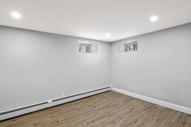 basement with light wood-type flooring and a baseboard heating unit