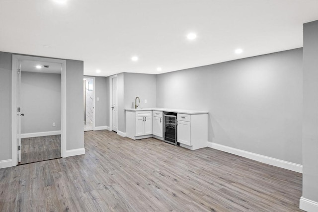 interior space featuring sink, white cabinetry, light hardwood / wood-style flooring, and wine cooler