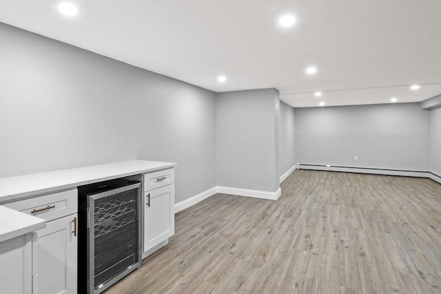 interior space featuring a baseboard radiator, light hardwood / wood-style floors, white cabinetry, and wine cooler