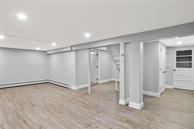 basement with light wood-type flooring and a baseboard heating unit