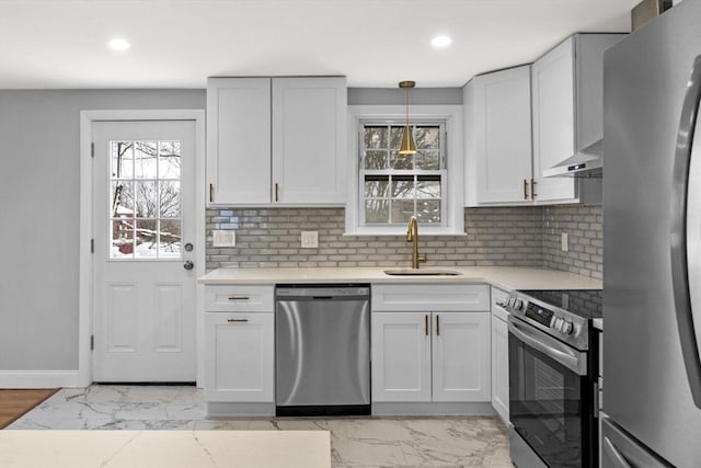 kitchen featuring pendant lighting, white cabinets, stainless steel appliances, tasteful backsplash, and sink