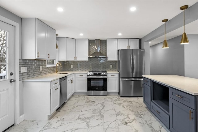 kitchen featuring decorative backsplash, wall chimney range hood, sink, decorative light fixtures, and stainless steel appliances