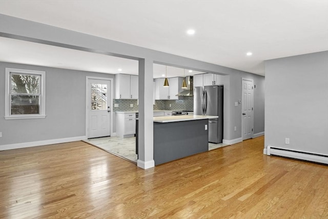 kitchen with white cabinetry, wall chimney range hood, pendant lighting, backsplash, and stainless steel appliances