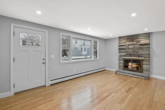 interior space featuring a baseboard radiator, a stone fireplace, and light wood-type flooring