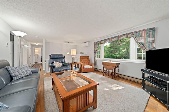 1102 State Rd, Plymouth, MA 02360 - living area featuring a wall mounted air conditioner, light wood-style floors, a textured ceiling, and baseboard heating