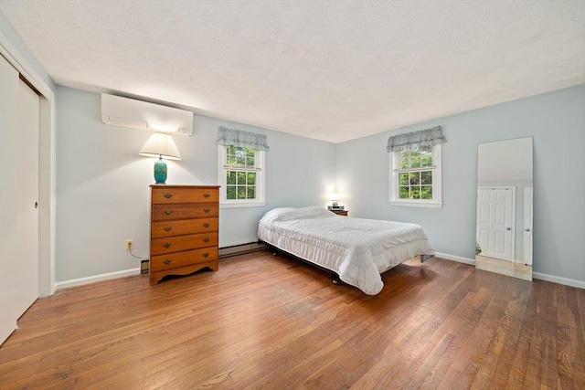 1102 State Rd, Plymouth, MA 02360 - bedroom featuring a wall mounted AC, wood-type flooring, baseboard heating, and multiple windows