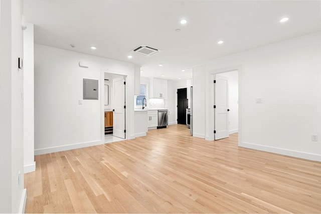 63 Oak St Unit 2, Somerville, MA 02143 - unfurnished living room with light wood-type flooring, electric panel, a sink, recessed lighting, and baseboards